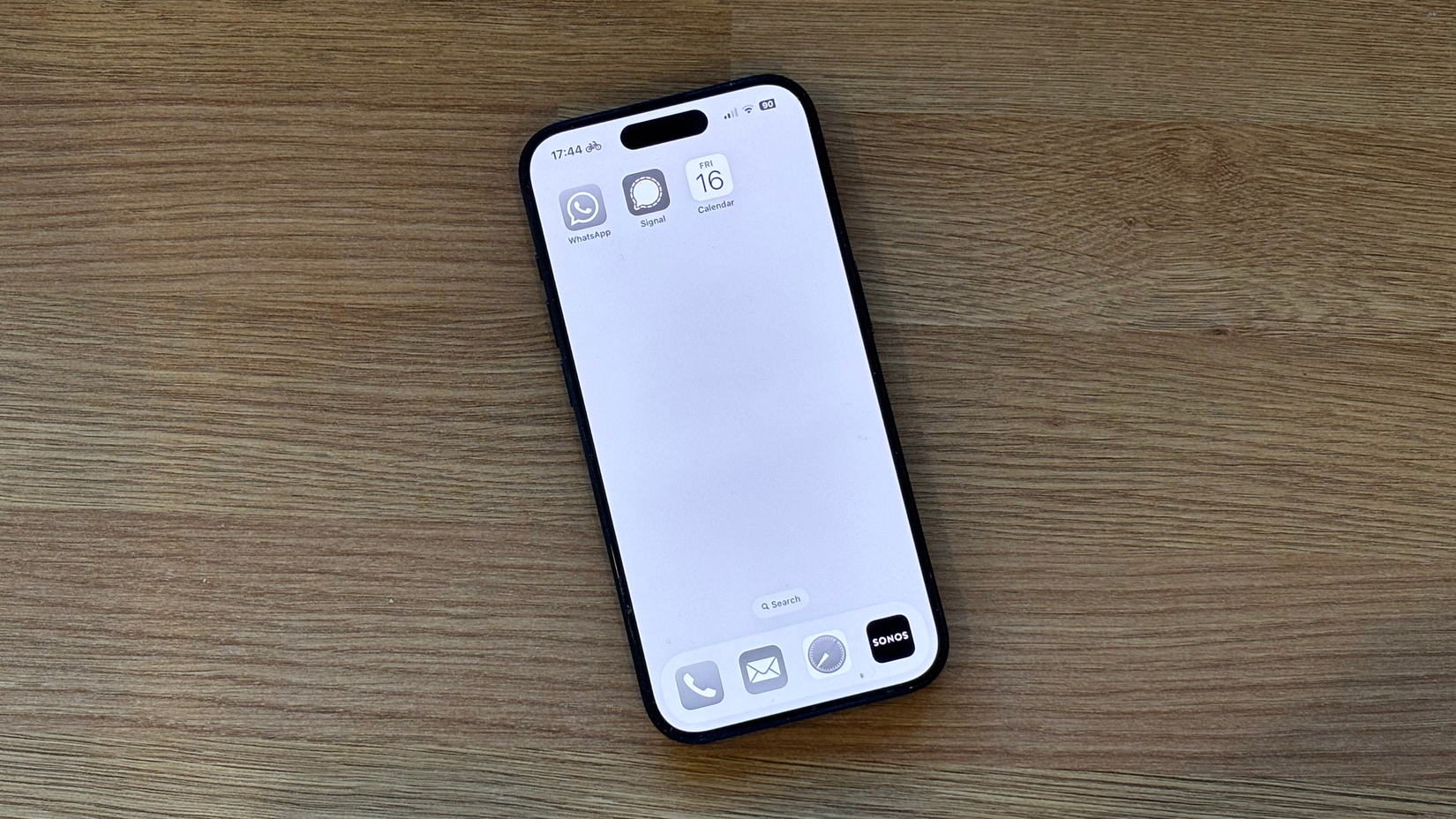 An iPhone with a grayscale Home Screen containing only three apps.